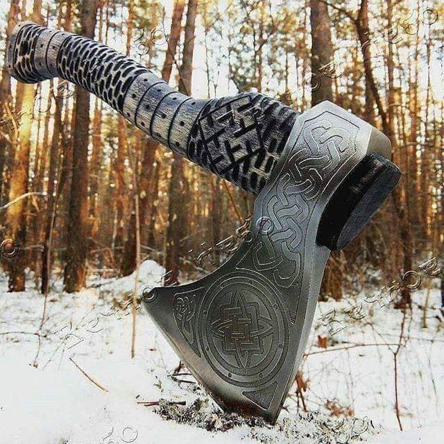 Decorative Viking axe with carved blade stuck in snow in winter forest