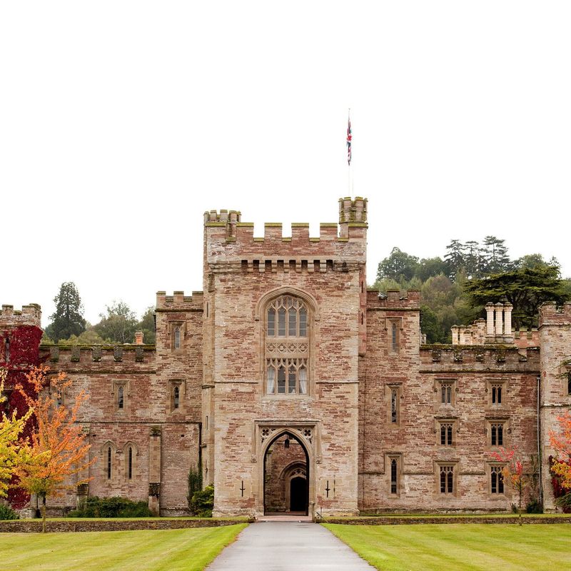 Stone castle with tower entrance, battlements, and pathway through green lawn