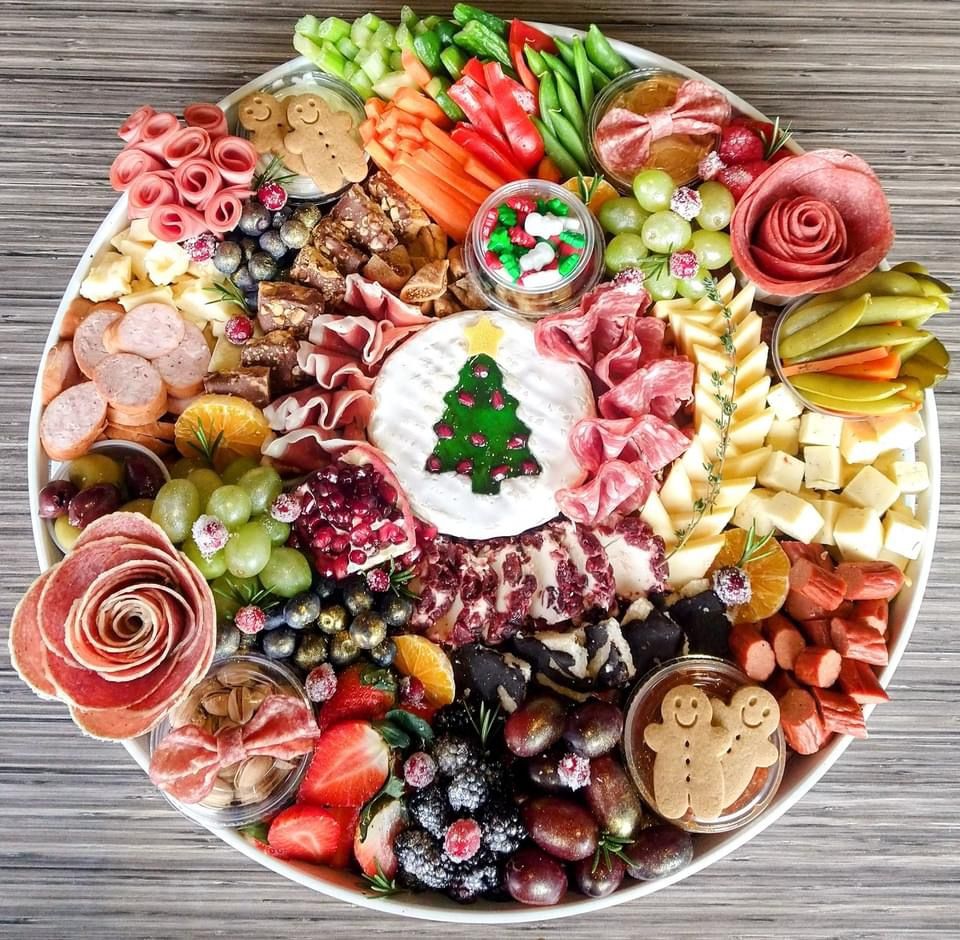 Overhead view of festive charcuterie board with meats, cheeses, berries, and Christmas tree centerpiece