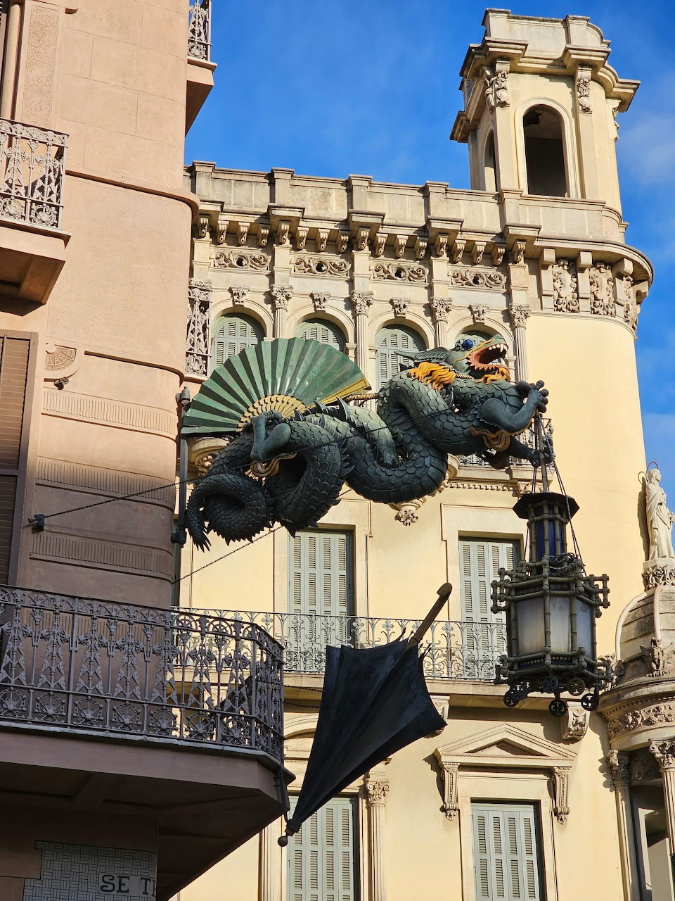 Ornate dragon sculpture mounted on a cream-colored building in Barcelona with architectural details
