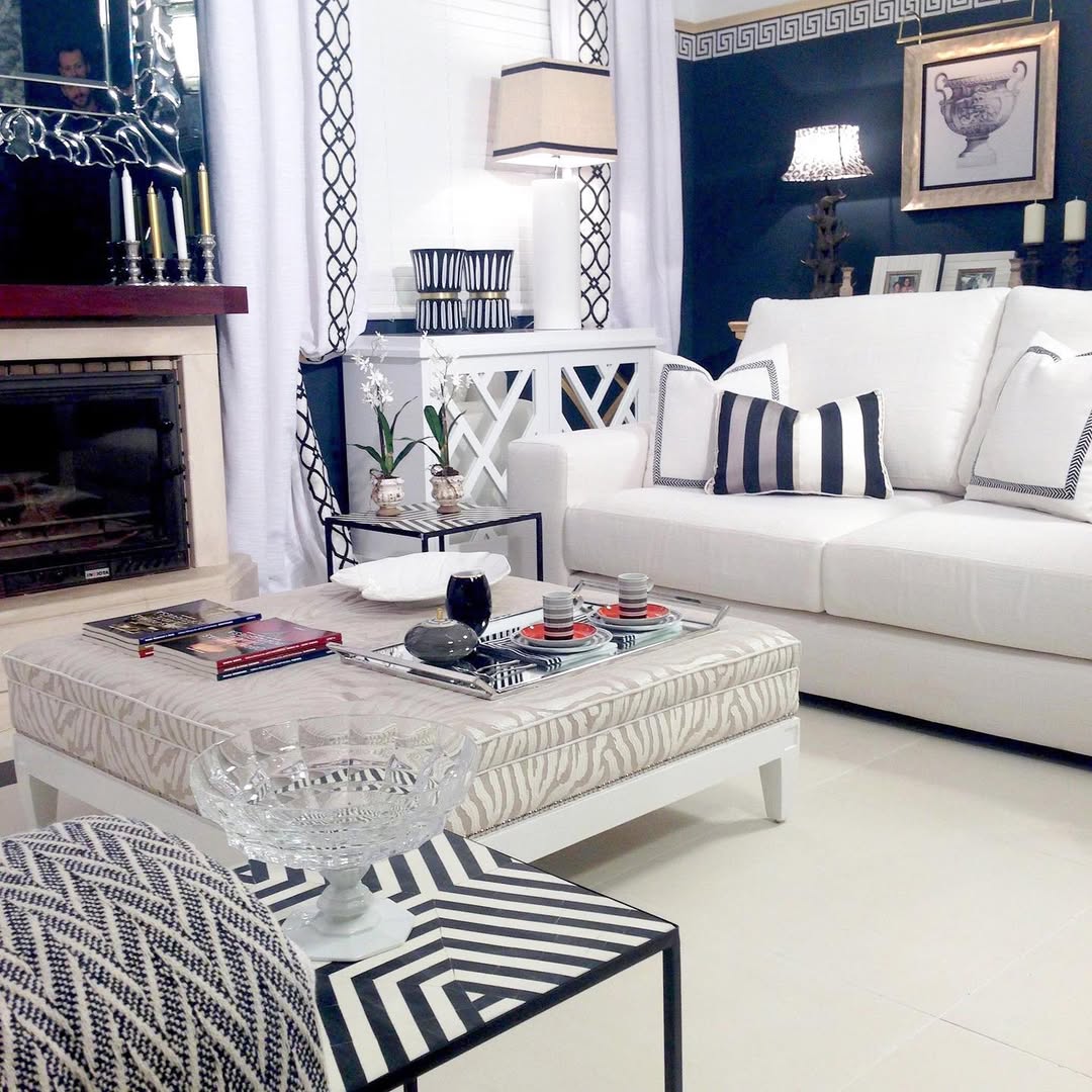 Modern living room with navy blue wall, white furniture, patterned textiles, fireplace and natural light from windows