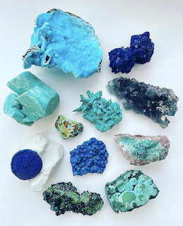 Collection of blue and turquoise minerals, gems, and rocks arranged on a white surface