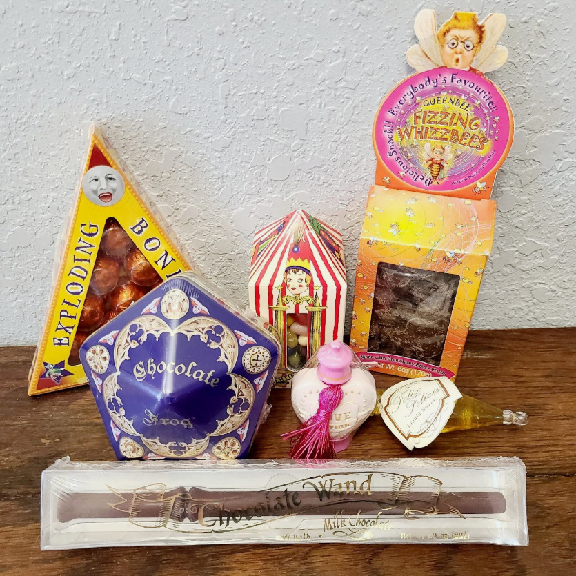 Assortment of Harry Potter themed candy boxes and collectible wand on table
