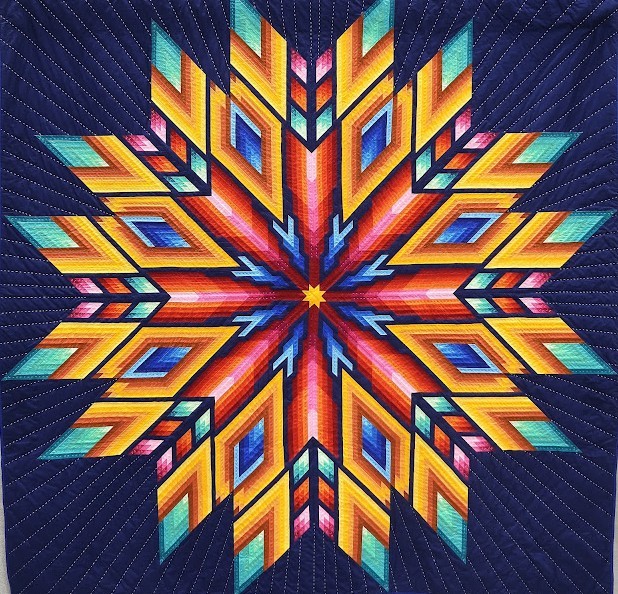 Colorful geometric star quilt pattern on a dark blue stitched background