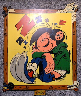 Cartoon of Gaston Lagaffe sleeping on the floor with his grey cat, large red Z letters floating above
