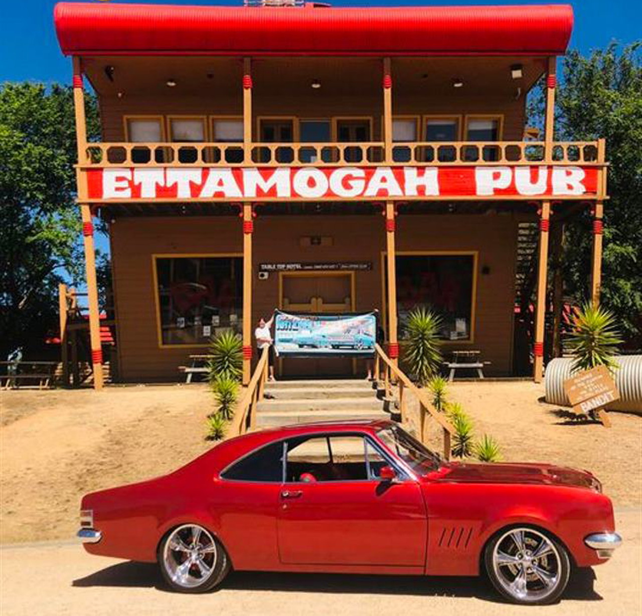 Red classic muscle car parked outside Ettamogah Pub building