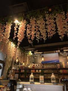 Cozy cafe interior with cascading white flowers, vintage shelves, and warm ambient lighting