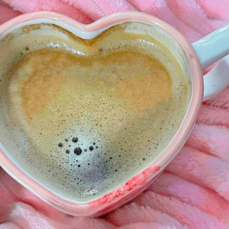 Frothy coffee in heart-shaped pink mug on pink knit blanket