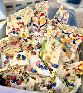 White chocolate bark pieces with colorful candy sprinkles and gold leaf in a bowl