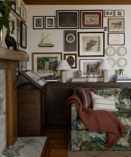 Cozy den with dark wood furniture, floral sofa, and gallery wall of framed art and decorative plates