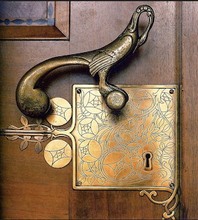 Vintage brass door handle with elaborate floral engravings mounted on weathered wood