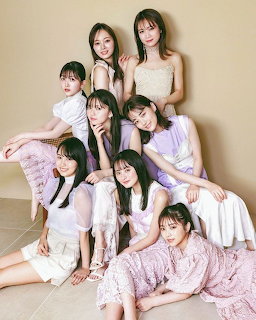 Eight young Japanese women in pastel clothing posing together for a group magazine photo