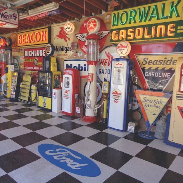 Vintage gas pumps and retro gasoline signs displayed indoors on a black and white checkered floor