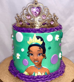 Birthday cake decorated with Princess Tiana face, turquoise and purple fondant, topped with golden crown