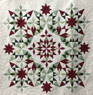 Alaska star quilt with geometric red and green star patterns on white fabric