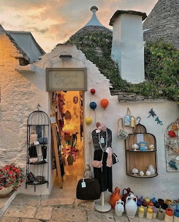 Whitewashed trulli building with conical roof and colorful shop display in Alberobello, Italy