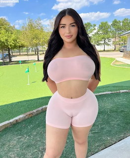 Woman in pink crop top and shorts standing at a putting green on a sunny day
