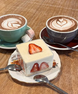 Strawberry shortcake slice with two lattes on wooden table