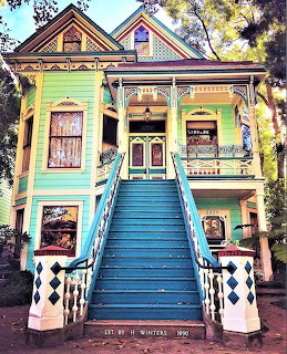 Colorful Victorian house with steep blue staircase and ornate painted trim in green, yellow, and teal