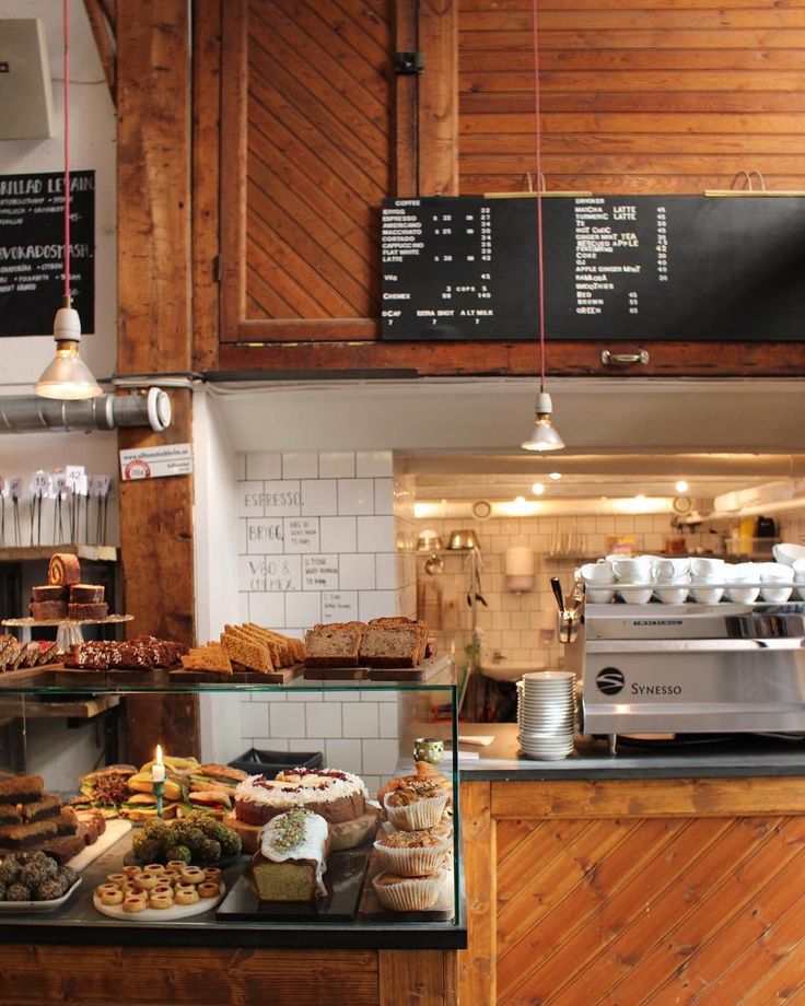 Warm vintage cafe interior with pastry display case, wooden cabinets, menu chalkboards, and espresso machine