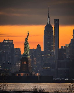New York City skyline silhouette with Statue of Liberty at sunset