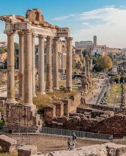 Ancient Roman Forum ruins with tall stone columns and the Colosseum in the background, Rome, Italy