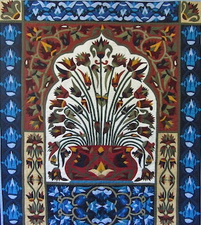 Decorative quilt with a stylized floral urn design and ornate blue and red borders