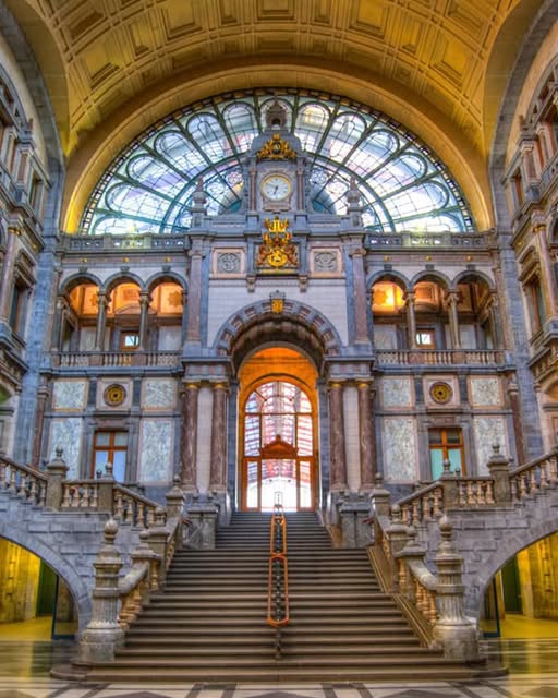 Ornate grand staircase inside Antwerp Central Station with marble columns and arched glass ceiling