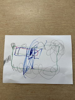 Child's drawing on white paper with colorful scribbles and shapes in blue, red, green, and black markers