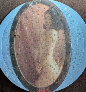 Round jigsaw puzzle with woman's portrait photo assembled on dark surface