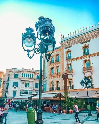 Decorative blue street lamp in a public square in Tunis with historic buildings and clear sky