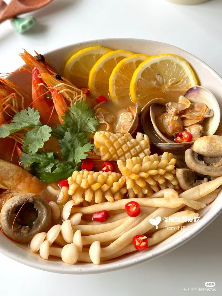 Korean seafood bowl with shrimp, clams, enoki mushrooms, lemon slices, and red chilies