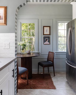 Kitchen nook with white walls, arched striped ceiling, desk between windows, and chair on rustrug