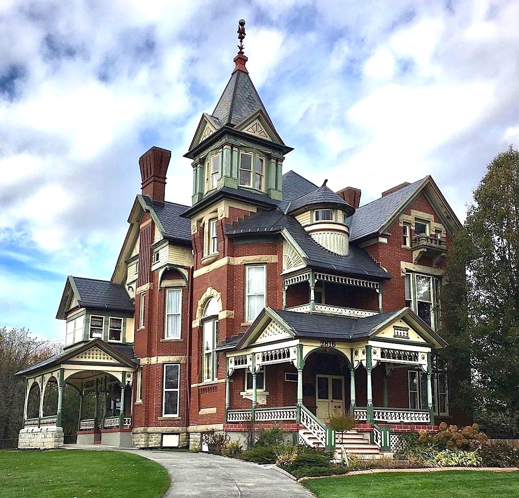 Victorian brick mansion with ornate porches and a tall central tower