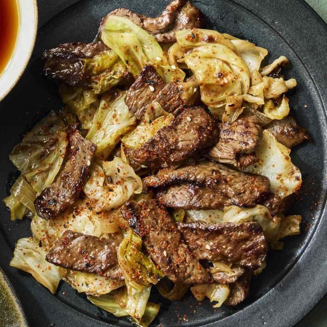Cooked beef strips and cabbage served in a dark bowl