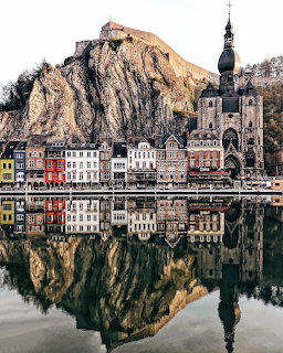 Historic European town with a church, cliff, and calm water reflection