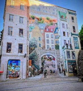 Large trompe-l'œil mural on a building wall showing historic Quebec City streets and colorful buildings