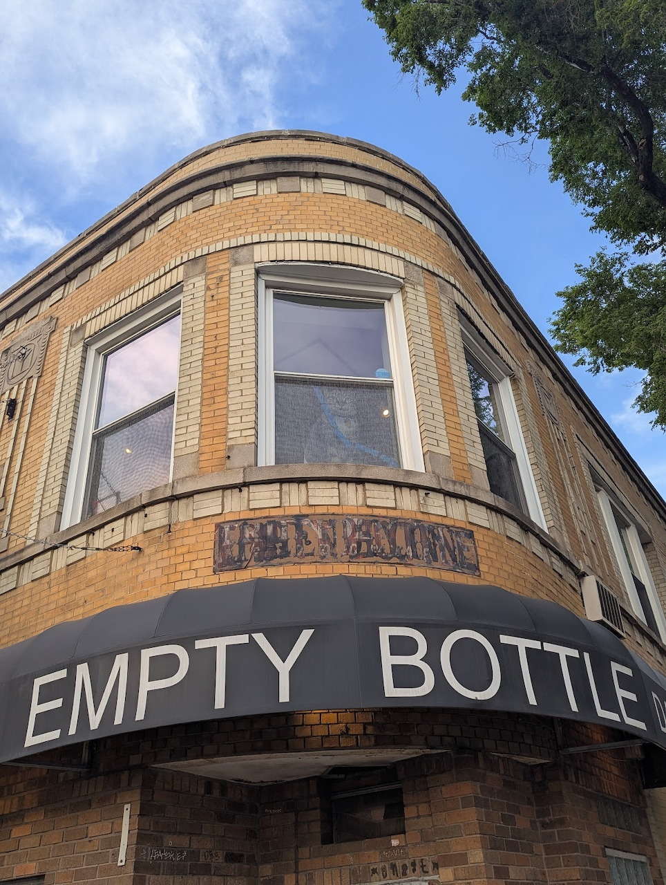Corner of the Empty Bottle music venue, a curved yellow brick building with large signage in Chicago