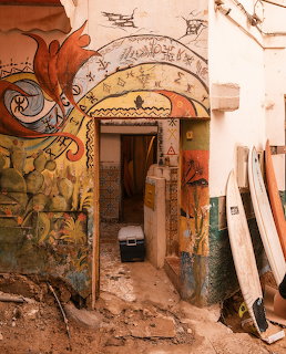 Painted archway doorway in Morocco with colorful murals and surfboards by the wall