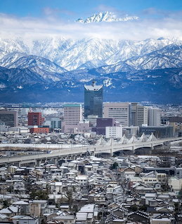 Snowy Tateyama mountains behind a Japanese city with buildings and elevated roads