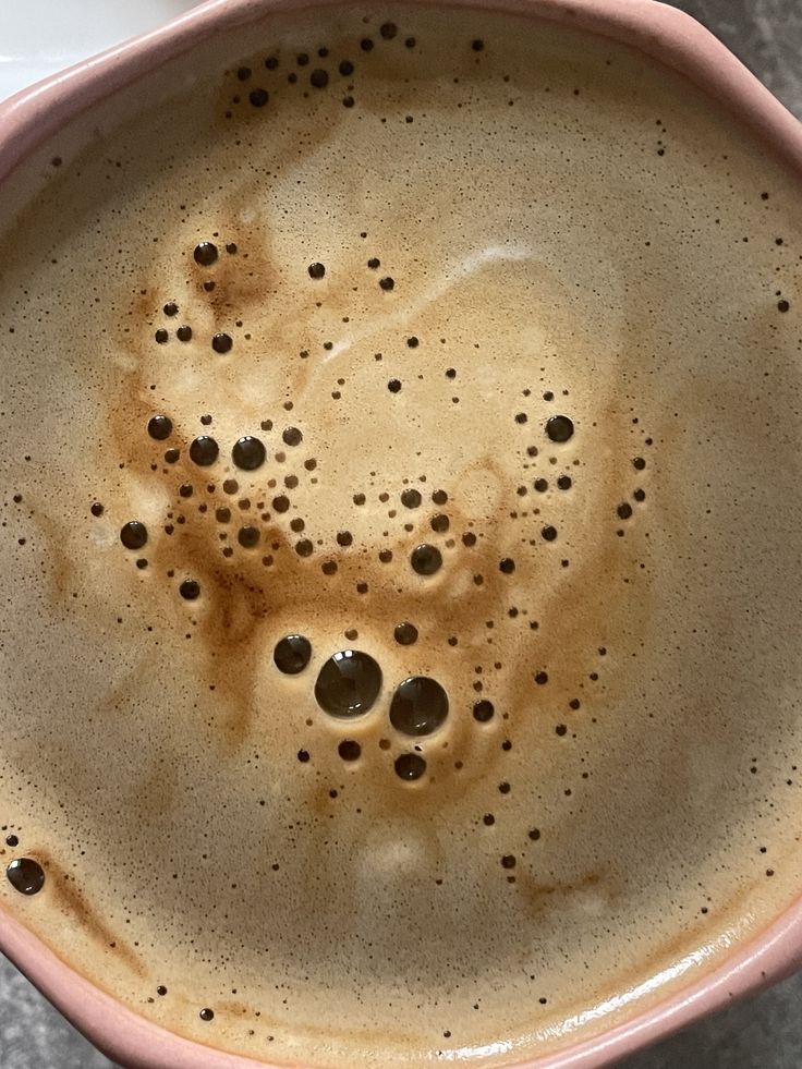 Overhead view of coffee with foam bubbles in a pink mug