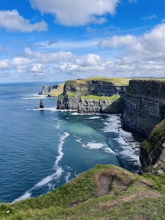 Tall coastal cliffs with ocean waves below and blue sky above