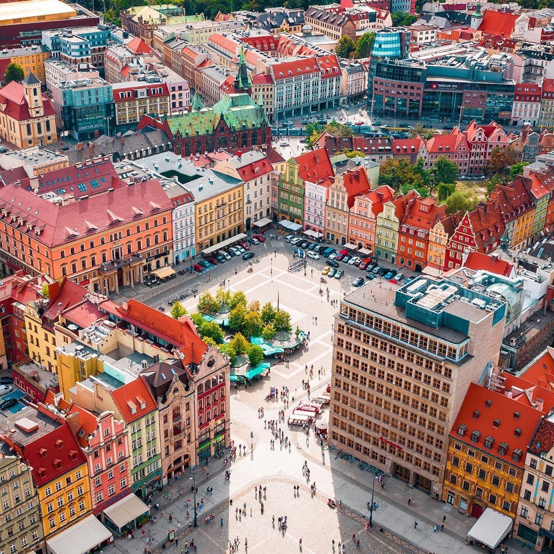 Aerial view of a European city square with colorful historic buildings and red rooftops