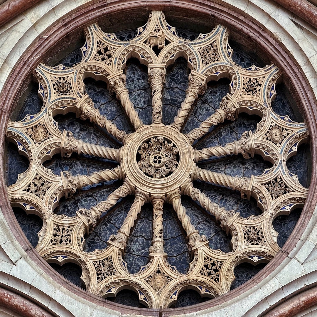 Ornate circular gothic rose window with radiating stone tracery and decorative carved patterns