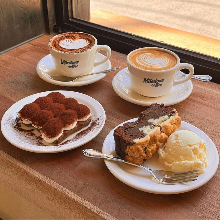 Two coffee cups with latte art, tiramisu, and waffle with ice cream on wooden table