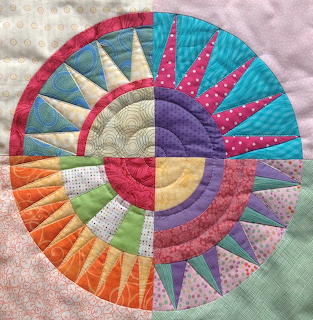 Circular fabric quilt with radiating sun pattern in bright multicolored segments