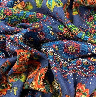 Close-up of folded blue fabric with colorful floral and geometric patterns