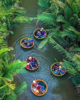 People in colorful tubes floating down a tropical river lined with palm trees