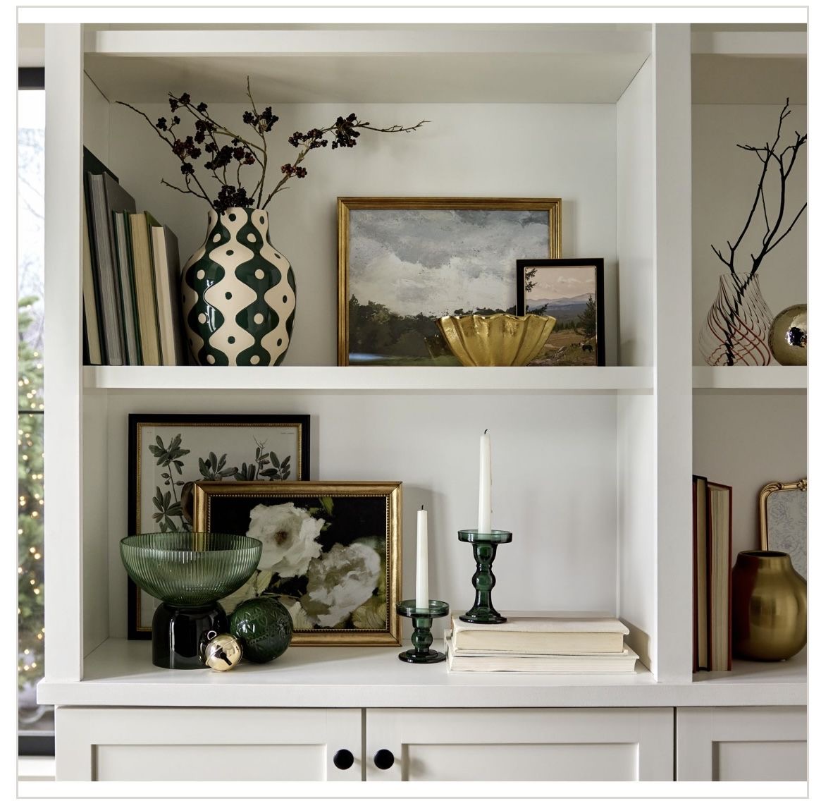 White shelves with framed art, decorative vases, candles, and ornamental objects in organized display