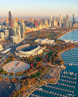 Aerial photo of Chicago skyline with Soldier Field stadium, harbor with boats, and downtown skyscrapers at sunset